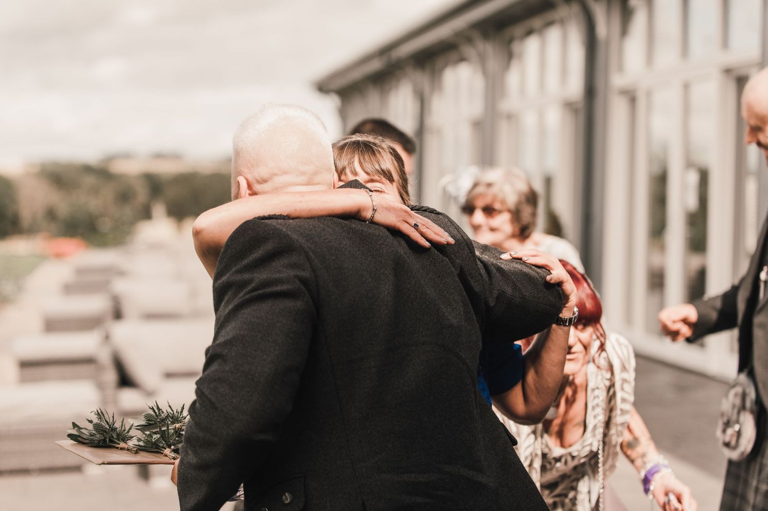 Warm embraces exchanged during emotional wedding reception moment outdoors.