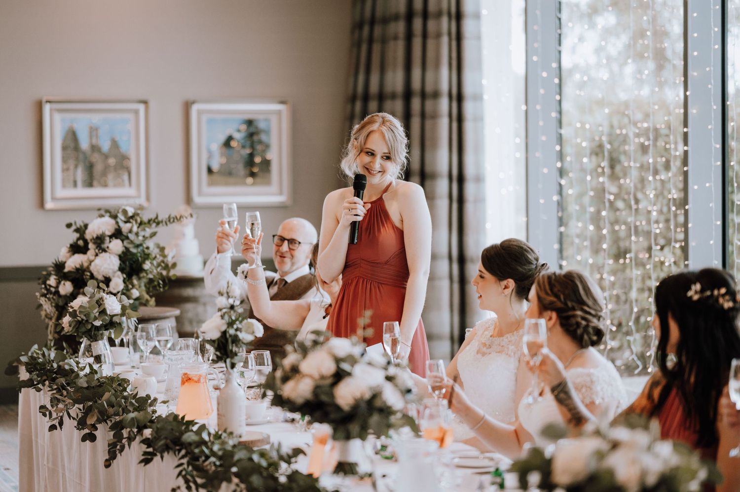 Wedding reception toast at decorated head table with floral garlands.