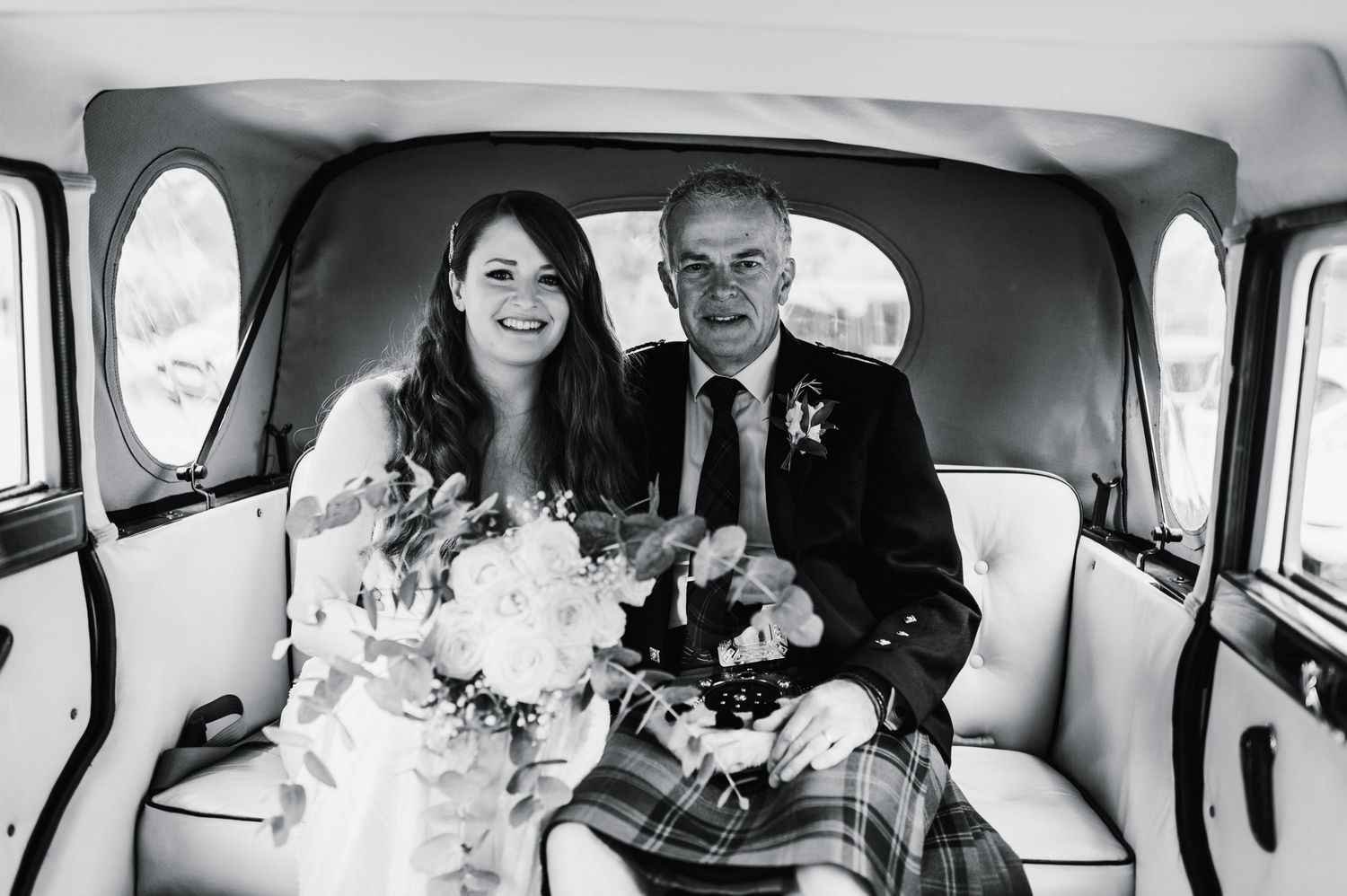 Classic vintage car interior with Scottish wedding attire and bridal bouquet.