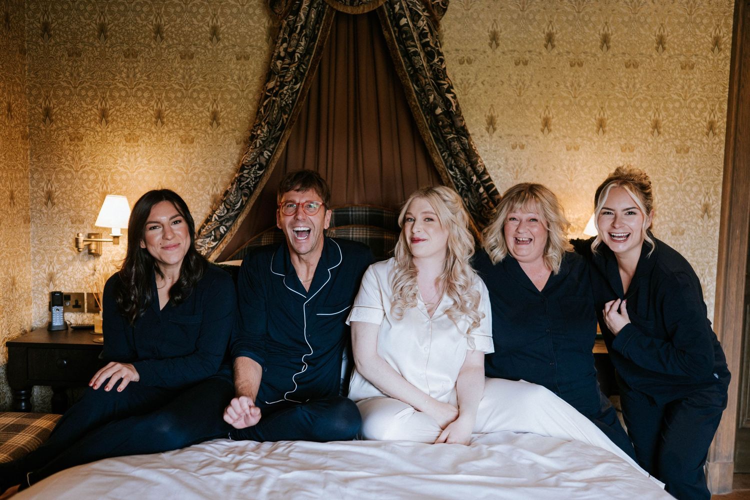 Group enjoying a fun moment together on a luxurious canopy bed.