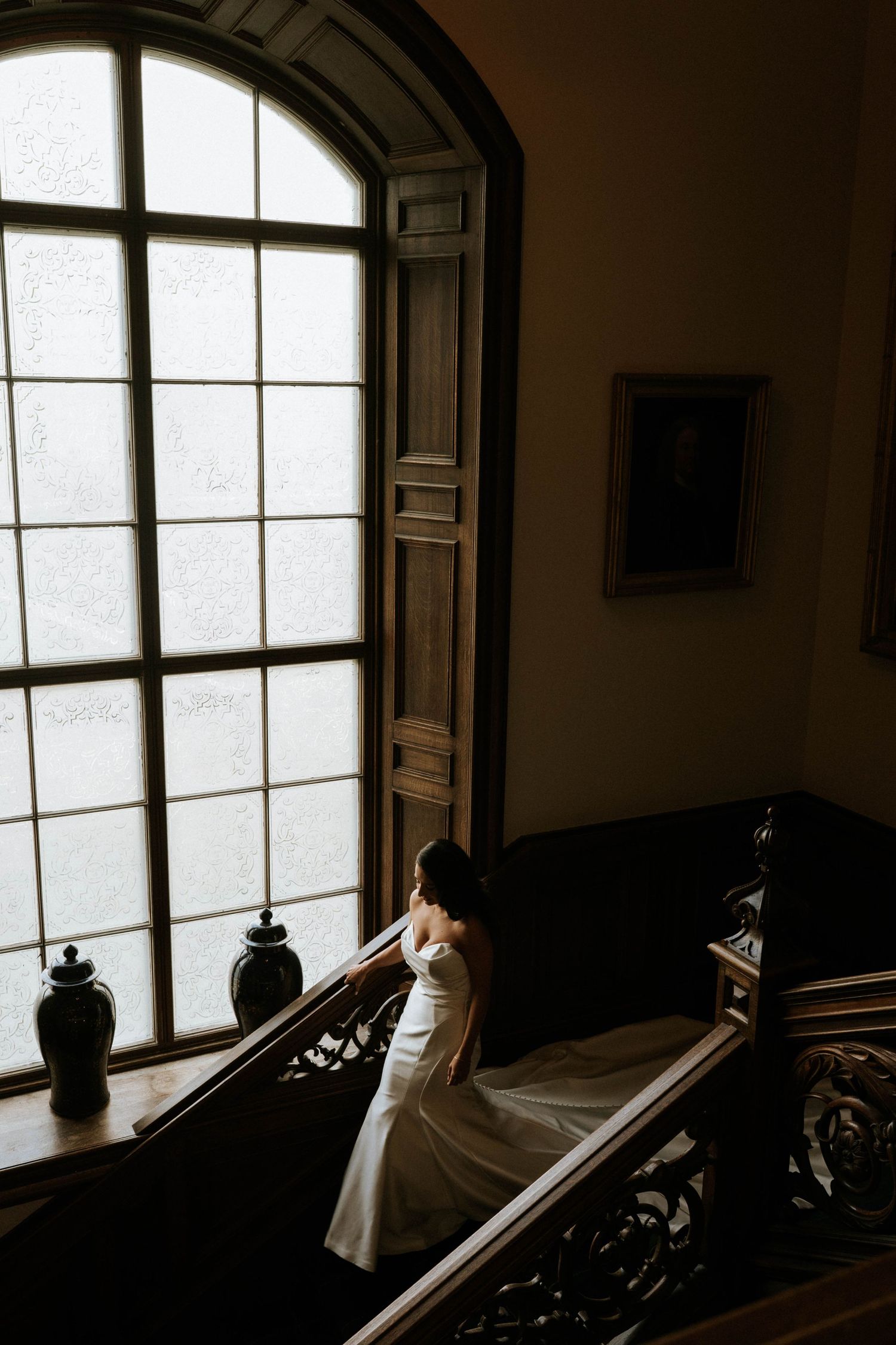 Dramatic window light streams into a dark room with arched windows and ornate details.
