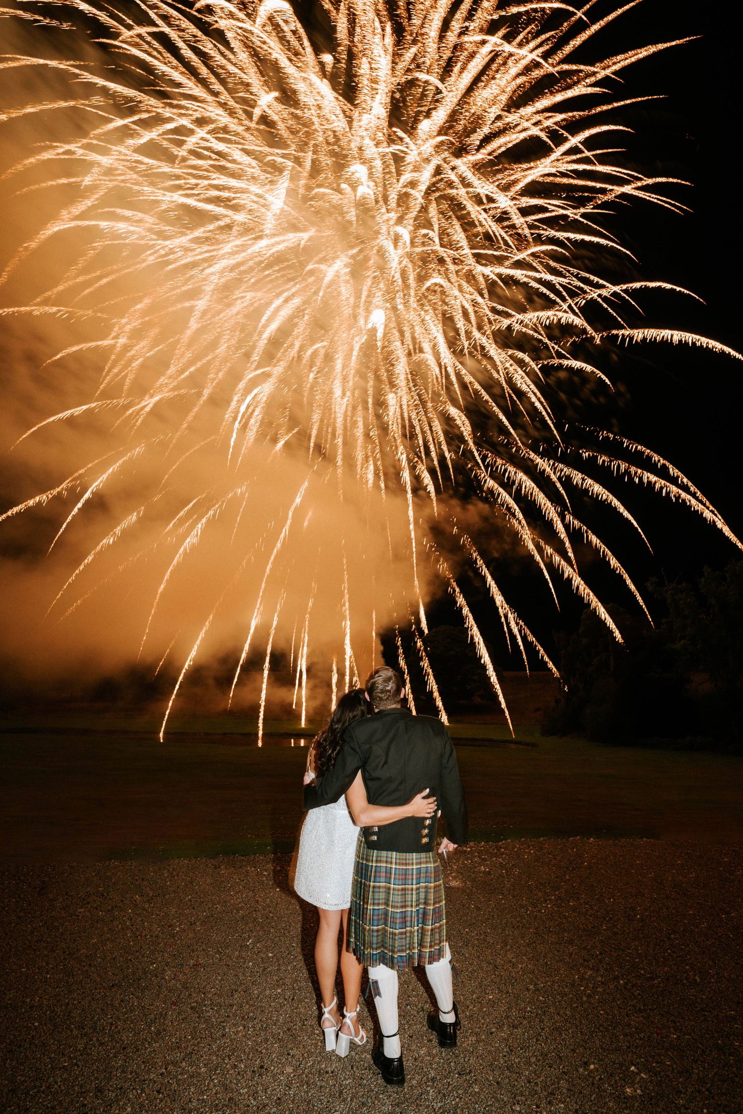 Golden fireworks illuminate the night sky during a romantic wedding celebration.
