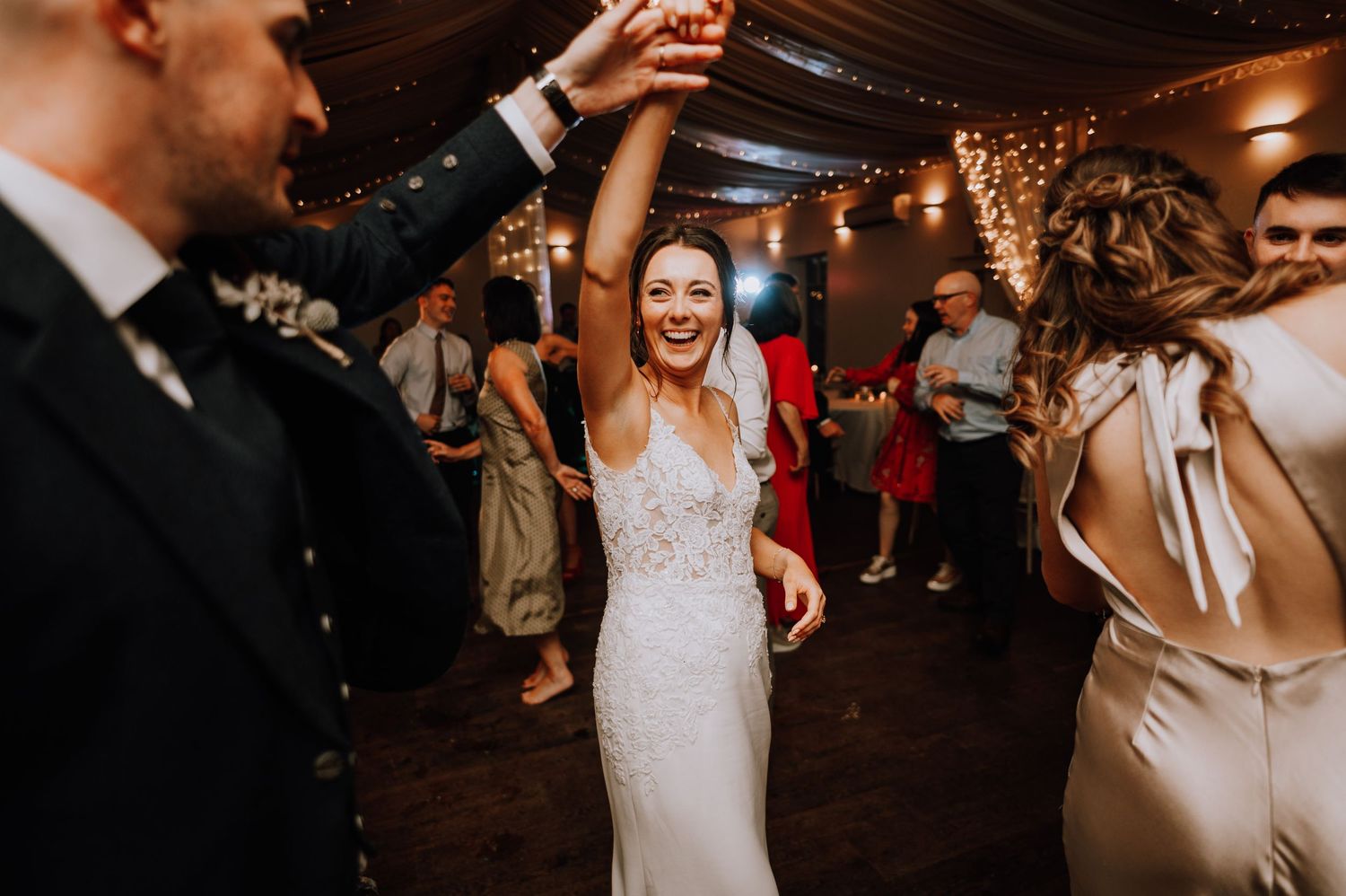 Aberdeen Wedding Photography. Wedding party dances and celebrates on a dimly lit dance floor with string lights overhead.