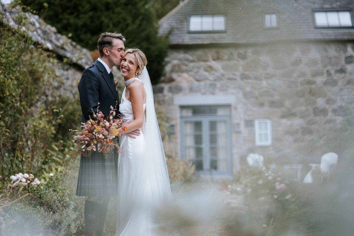 A romantic moment captured between newlyweds against rustic stone architecture.