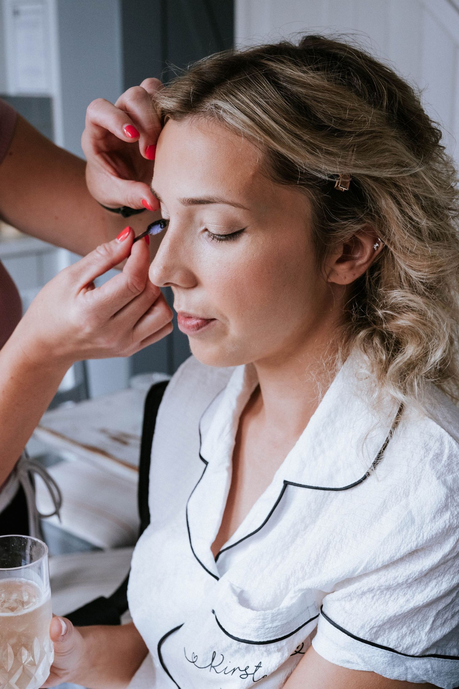 Close-up shots of someone getting makeup applied while wearing a white robe with black trim.