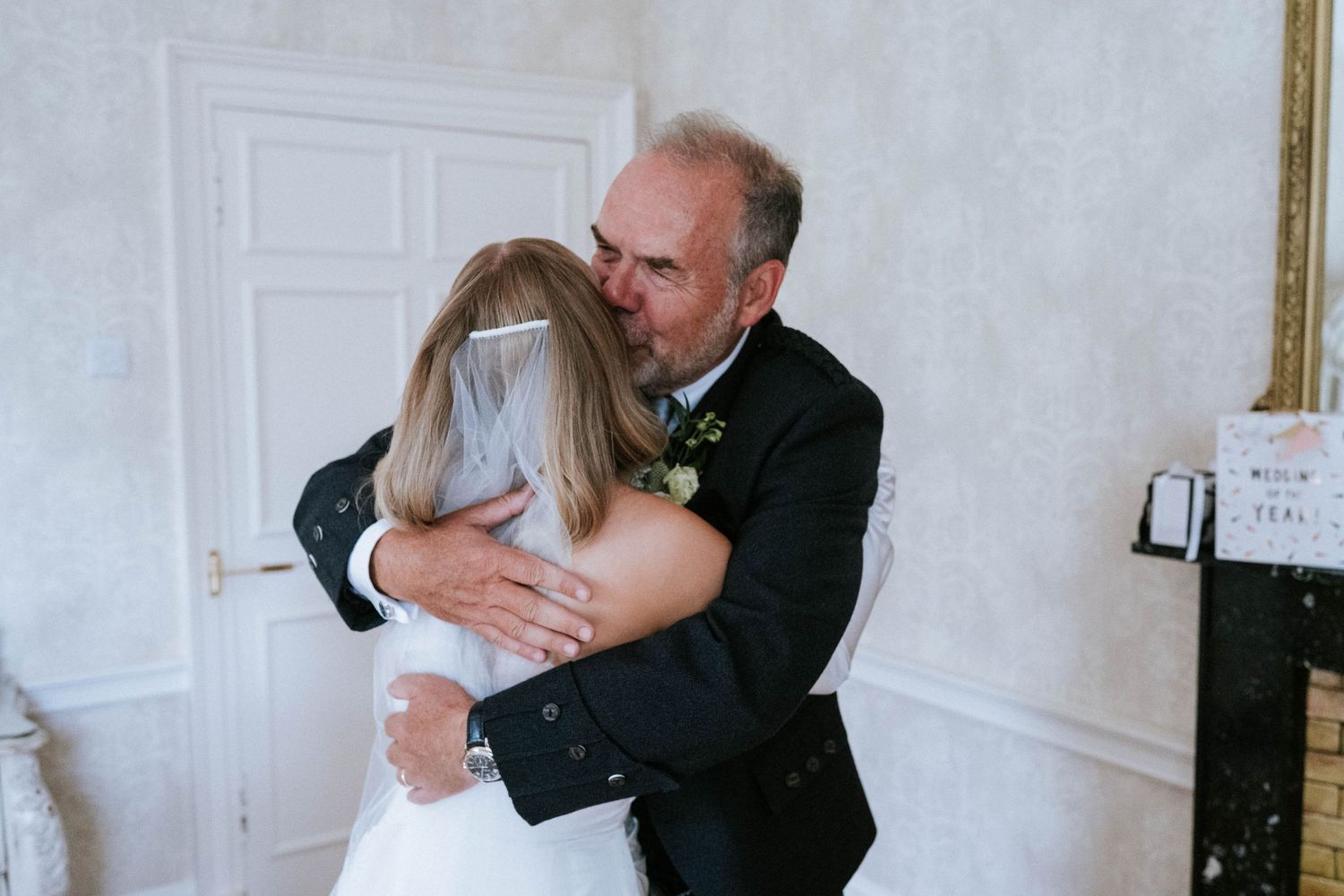 A couple in formal attire shares a romantic dance moment in an elegant white room.