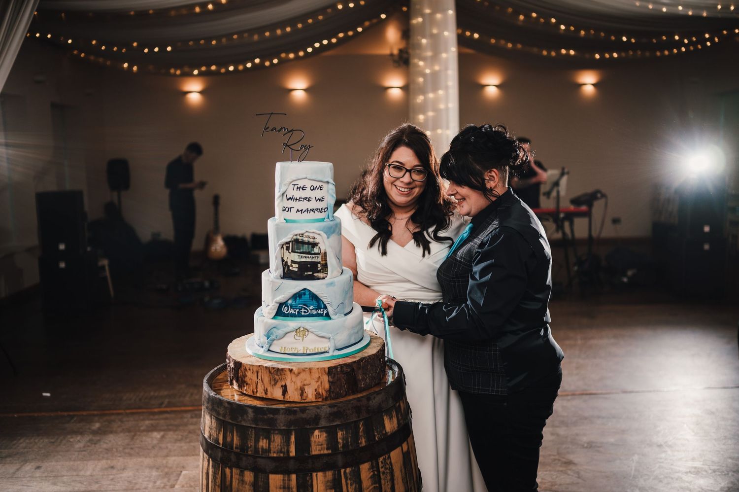 Logie House Wedding Photography. Couple cutting their mountain-themed wedding cake displayed on rustic wooden barrel.