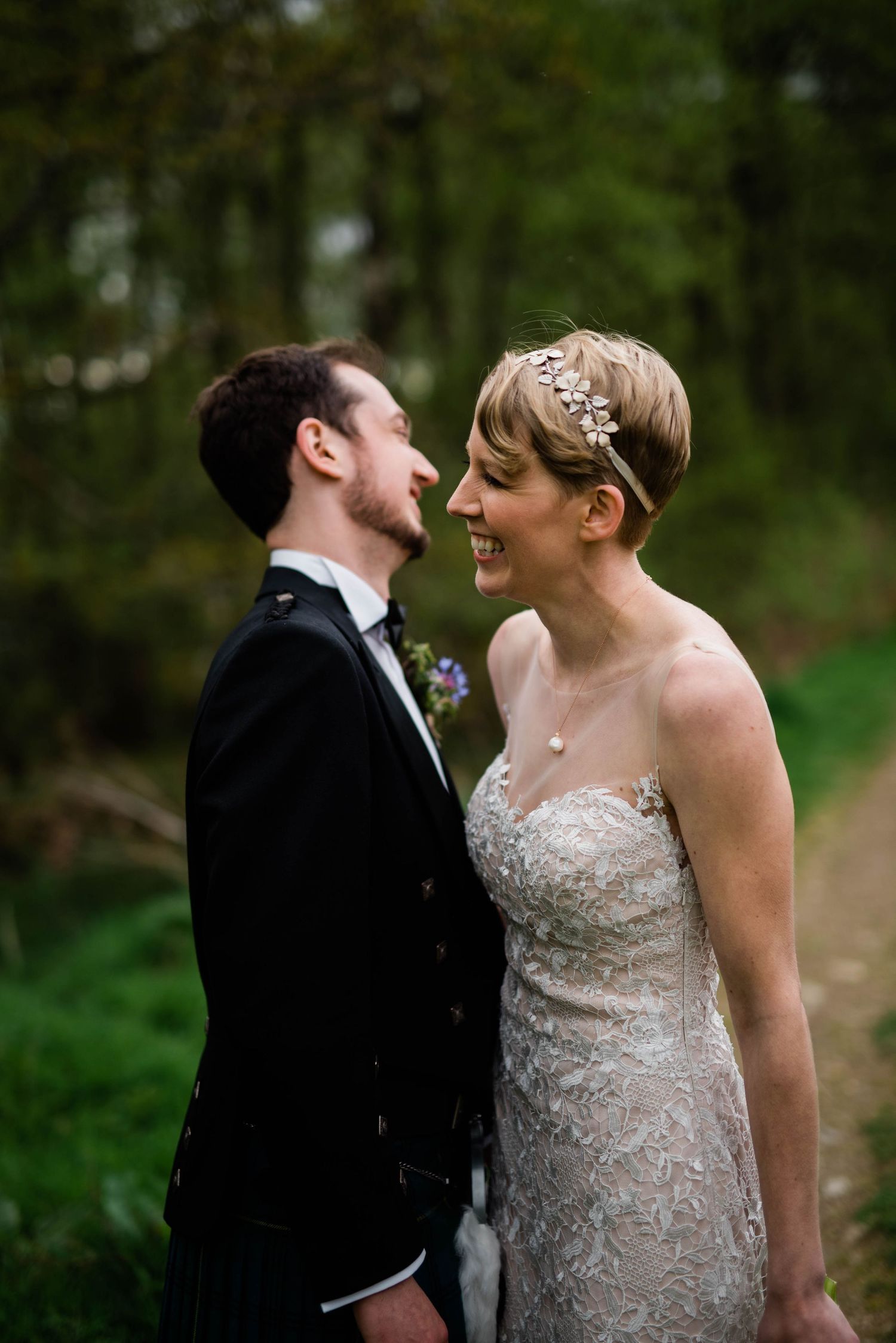 A joyful candid moment between newlyweds on their wedding day in a natural setting.