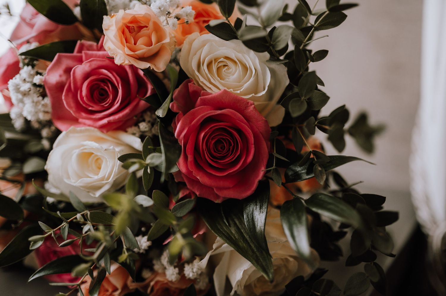 Close-up of an elegant floral arrangement featuring red and white roses with green foliage.