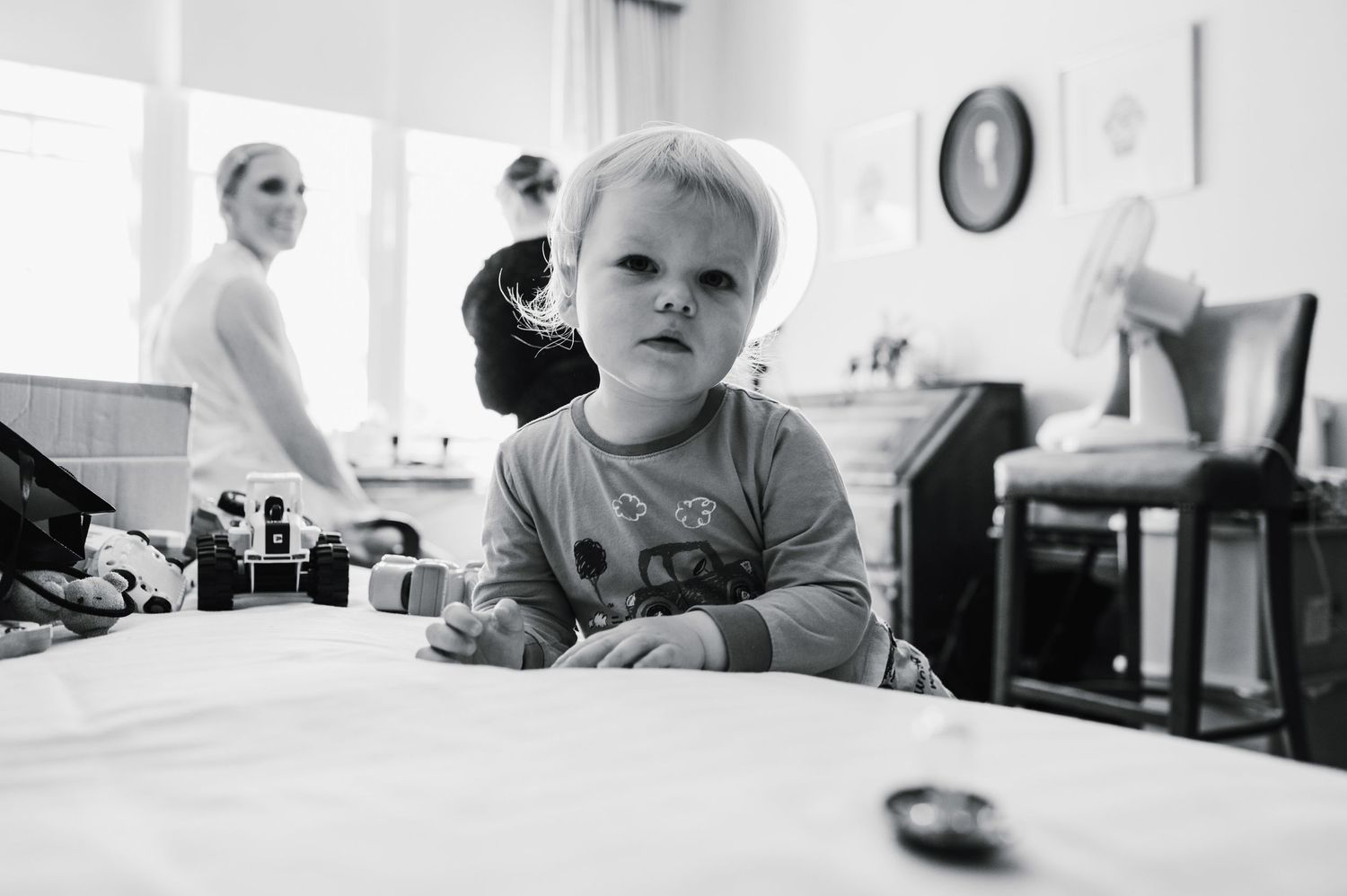 Black and white photo of toddler at table during wedding preparations.