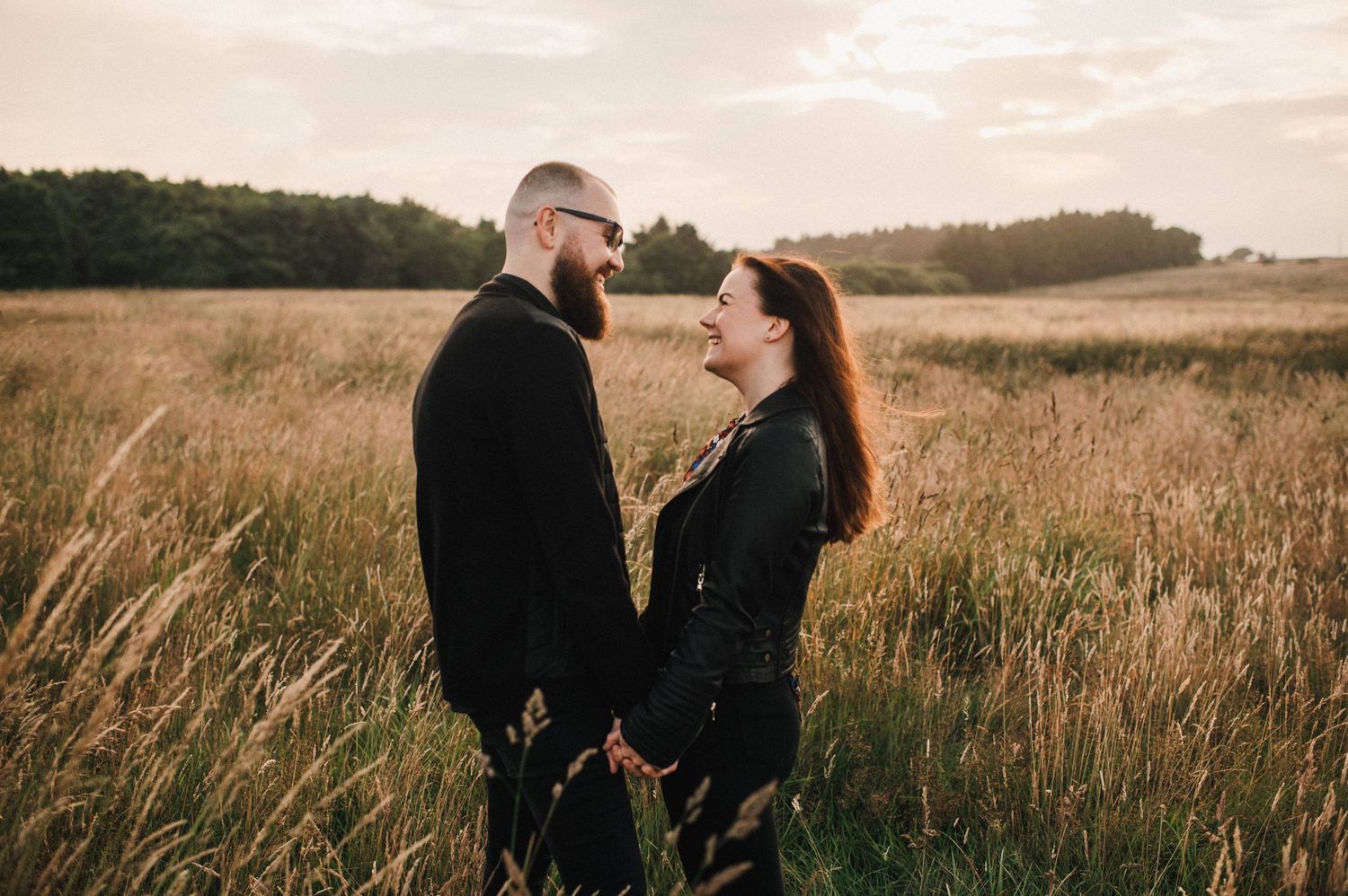 Two people in black outfits sharing a moment together in a sunlit meadow.