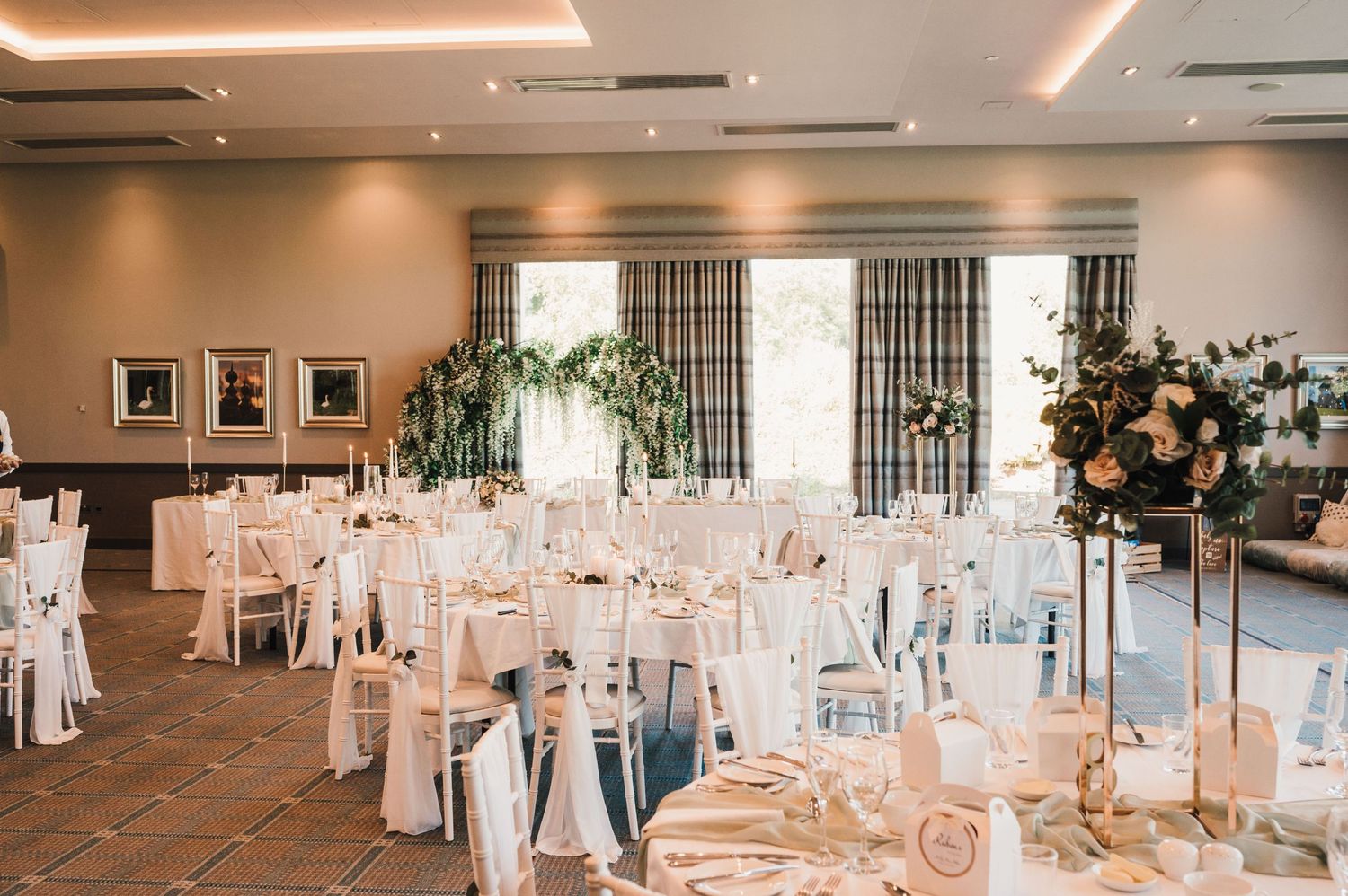 Elegant wedding reception room with tables set in white and gold decor.