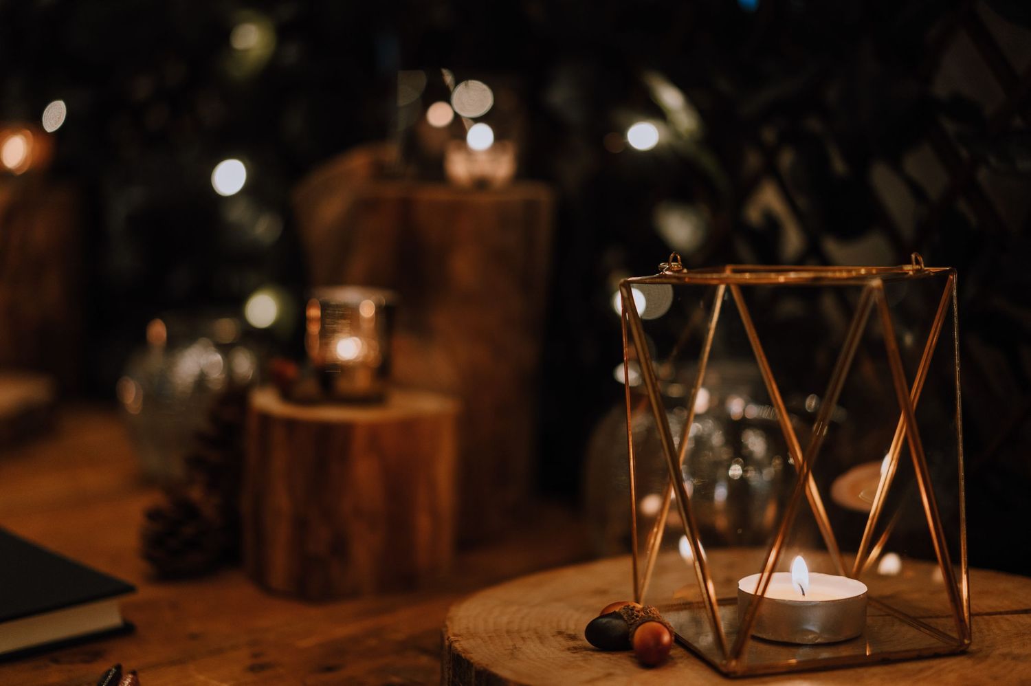 Geometric gold lantern with candle creates romantic ambiance on rustic wooden surface.