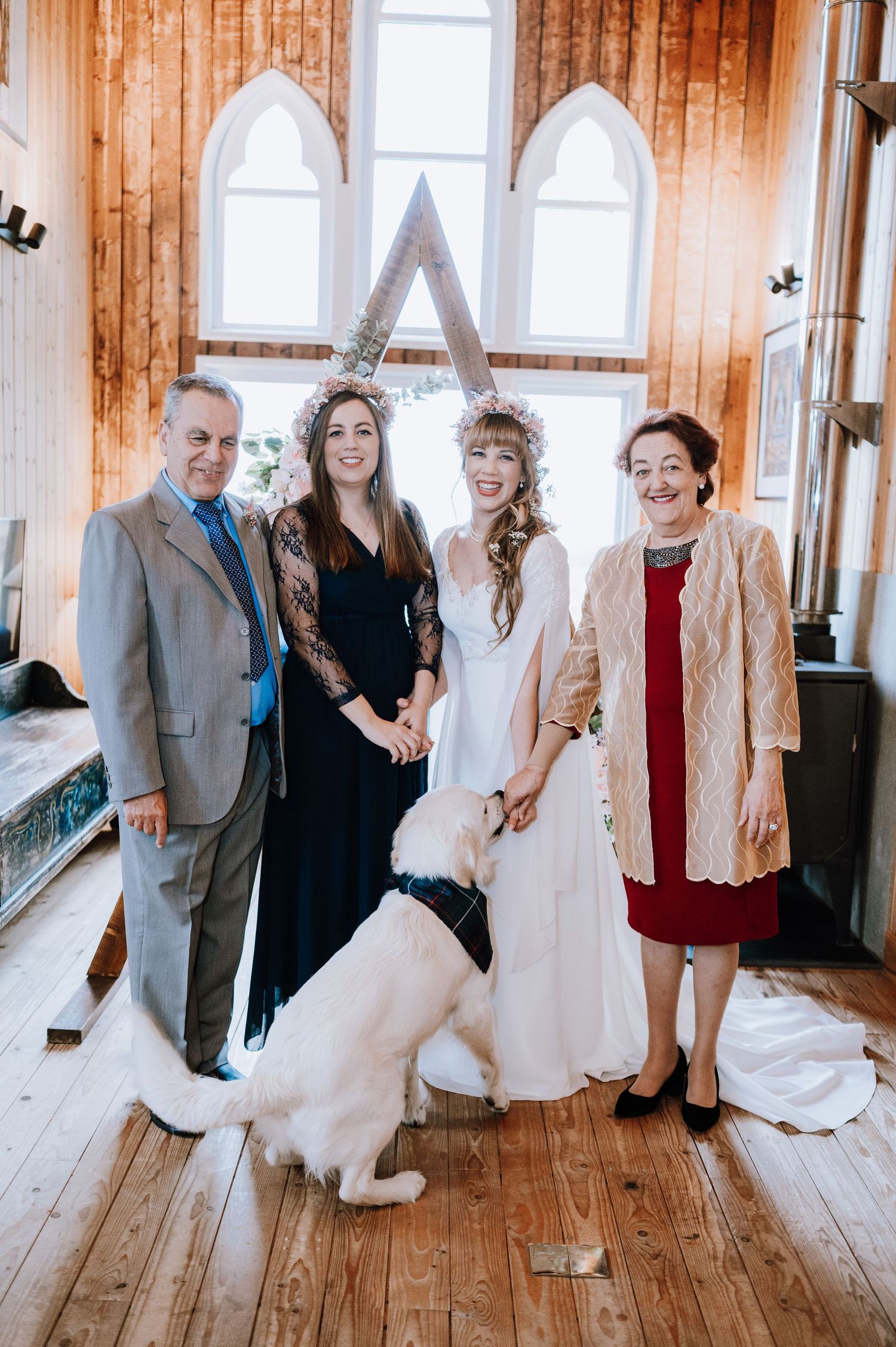 Wedding ceremony in rustic chapel with white dog and wooden A-frame backdrop.