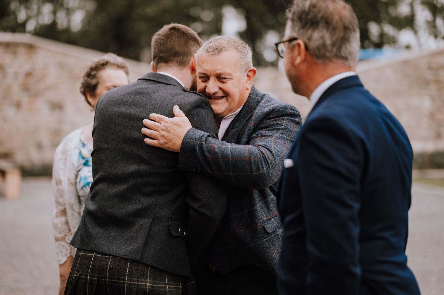 Emotional moment as guests embrace during outdoor wedding celebration.