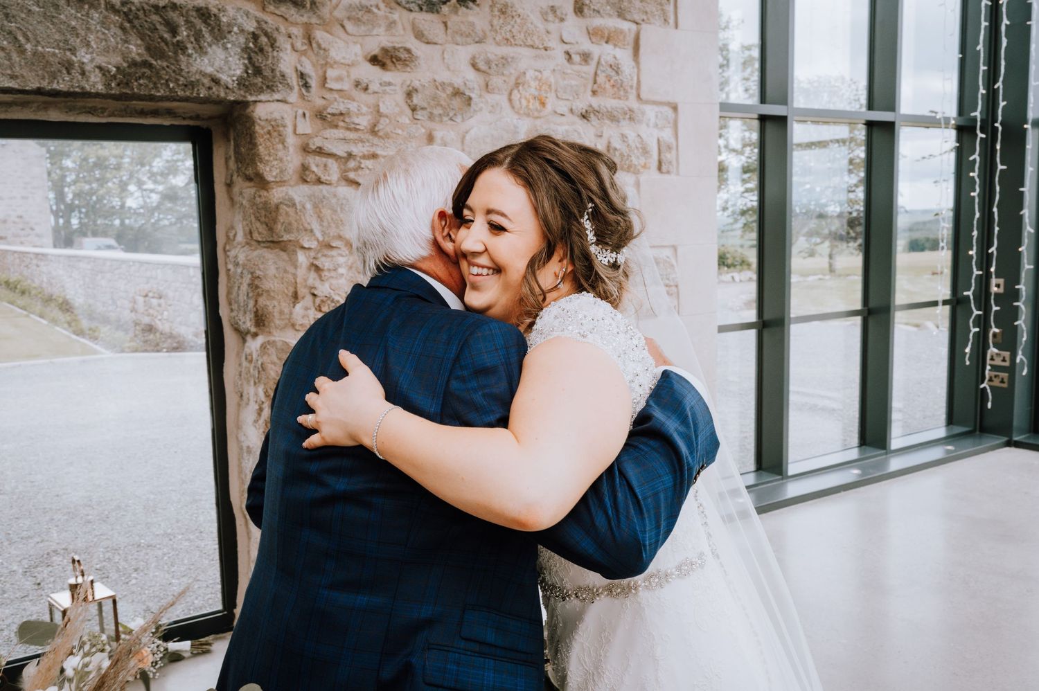 Joyful embrace captured during wedding celebration in stone-walled venue.