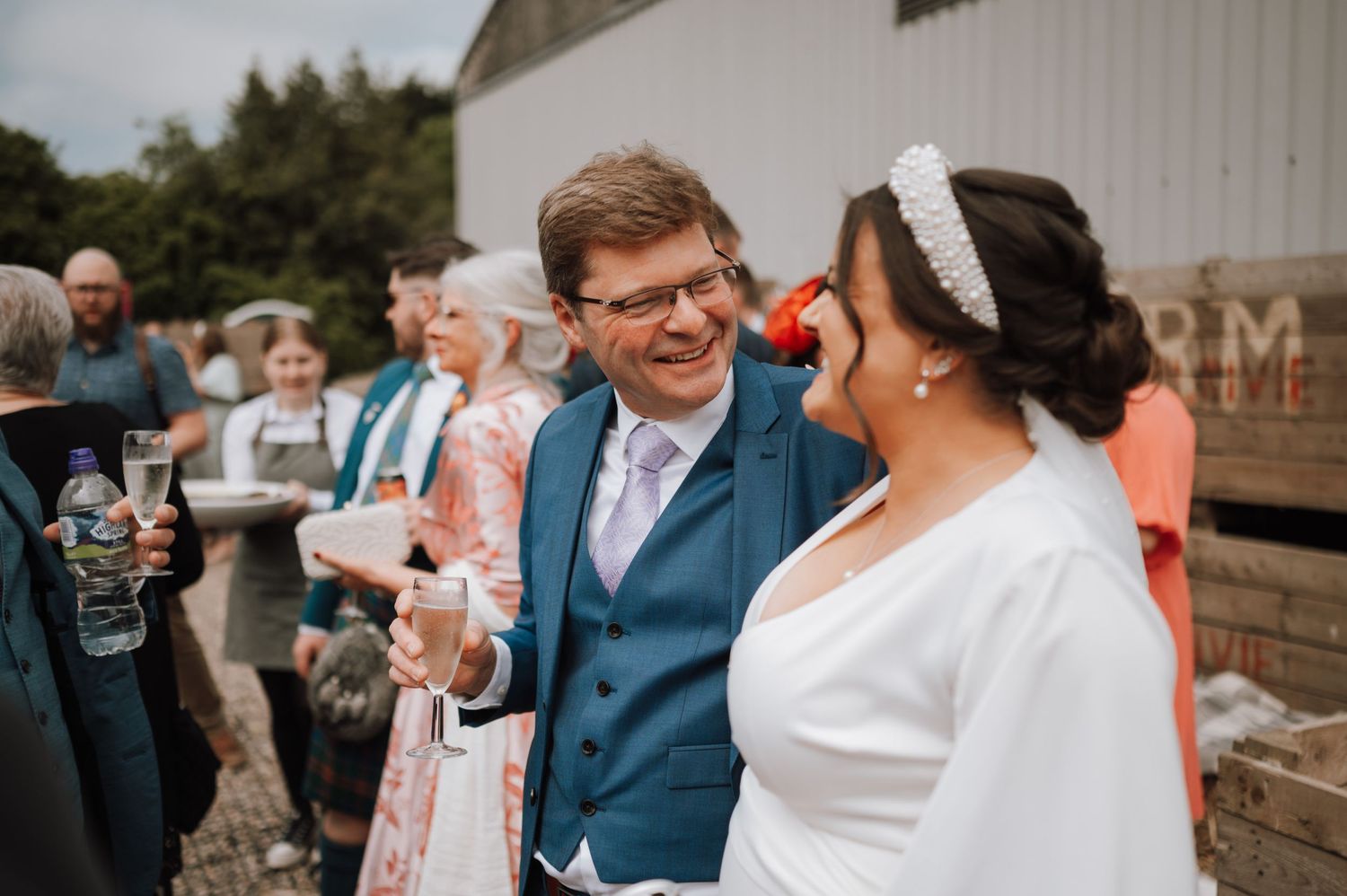 Wedding celebration outdoors with guests mingling and holding drinks.