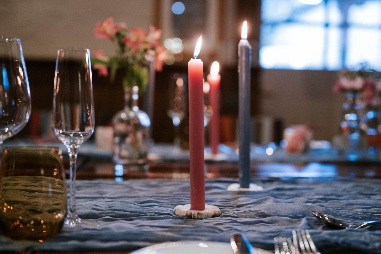 Elegant table setting with red candles, wine glasses and floral centerpieces for wedding reception.