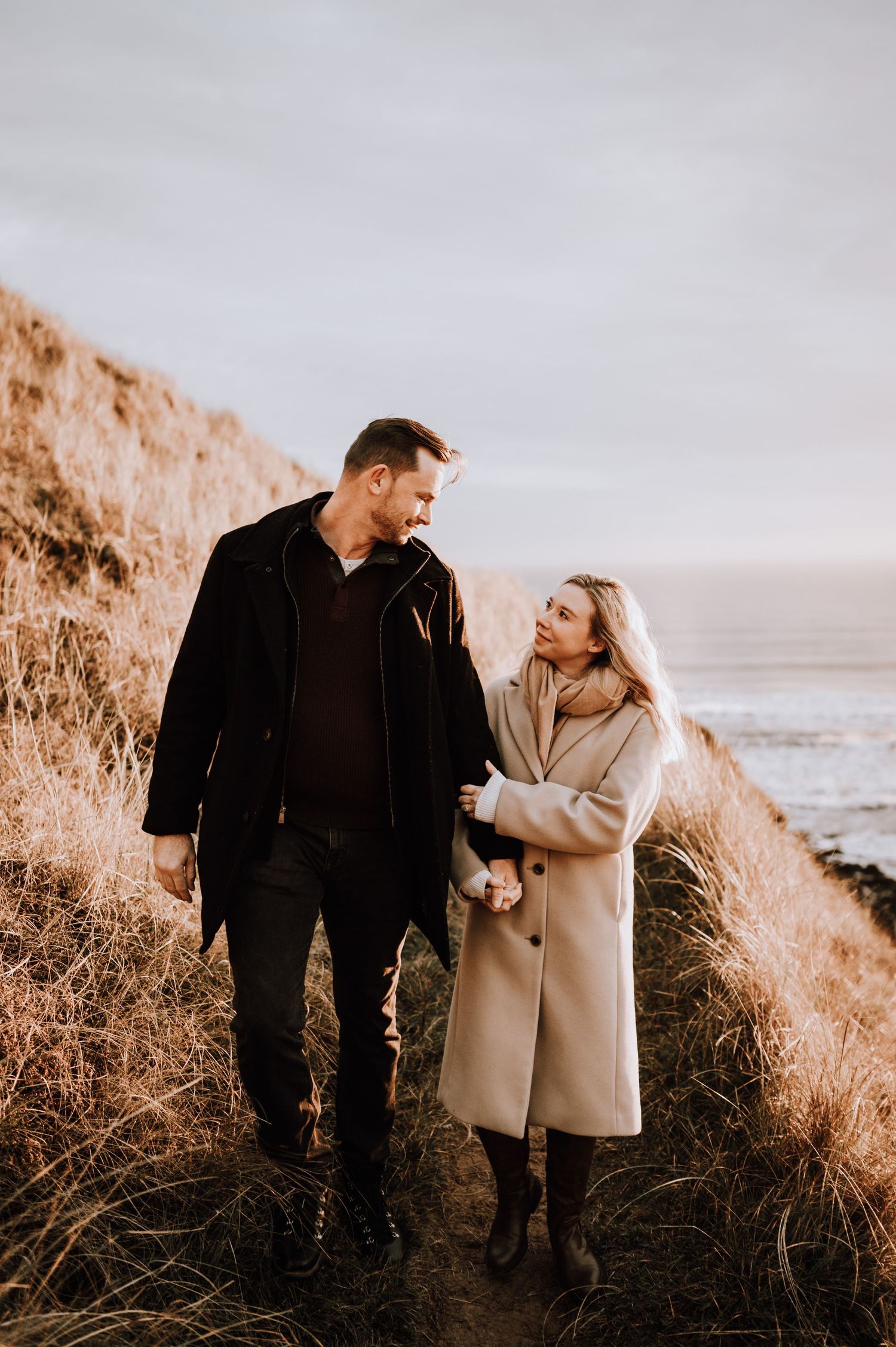 Couple shares joyful moment while hiking along dramatic oceanside cliffs.