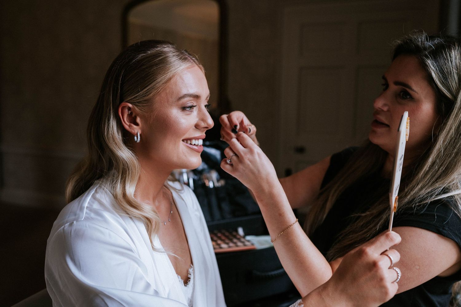 Makeup artist applying cosmetics during wedding preparation.