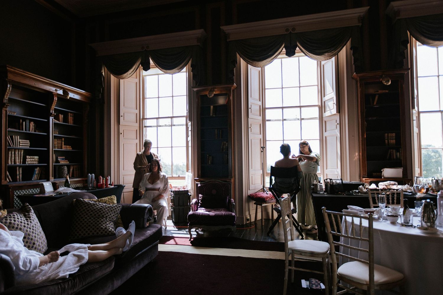 Silhouettes of people in a grand library room with tall windows.