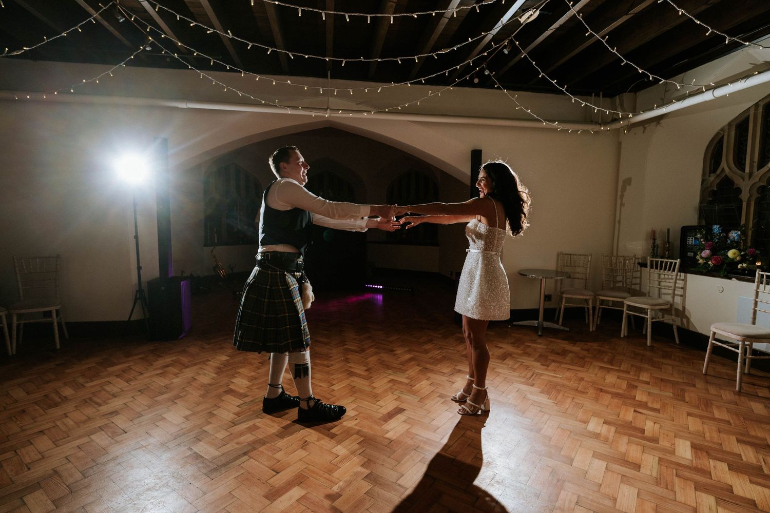 Wedding reception dance floor with string lights overhead as couples share romantic dances.
