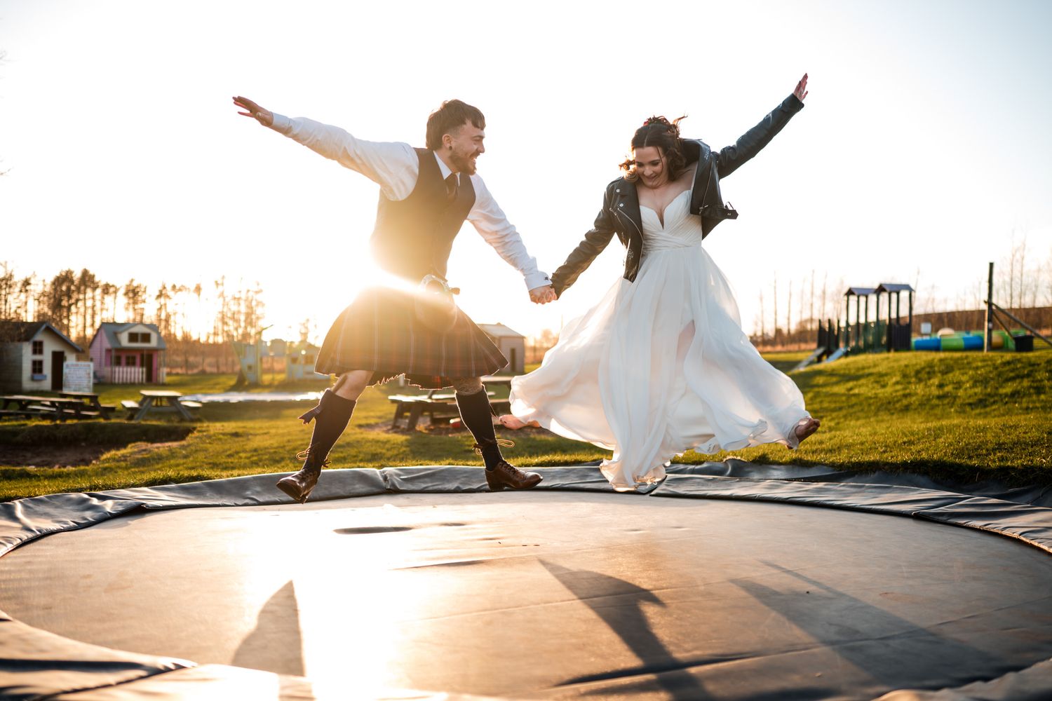 Wedding couple poses outdoors in dramatic sunset lighting with creative silhouettes and movements.