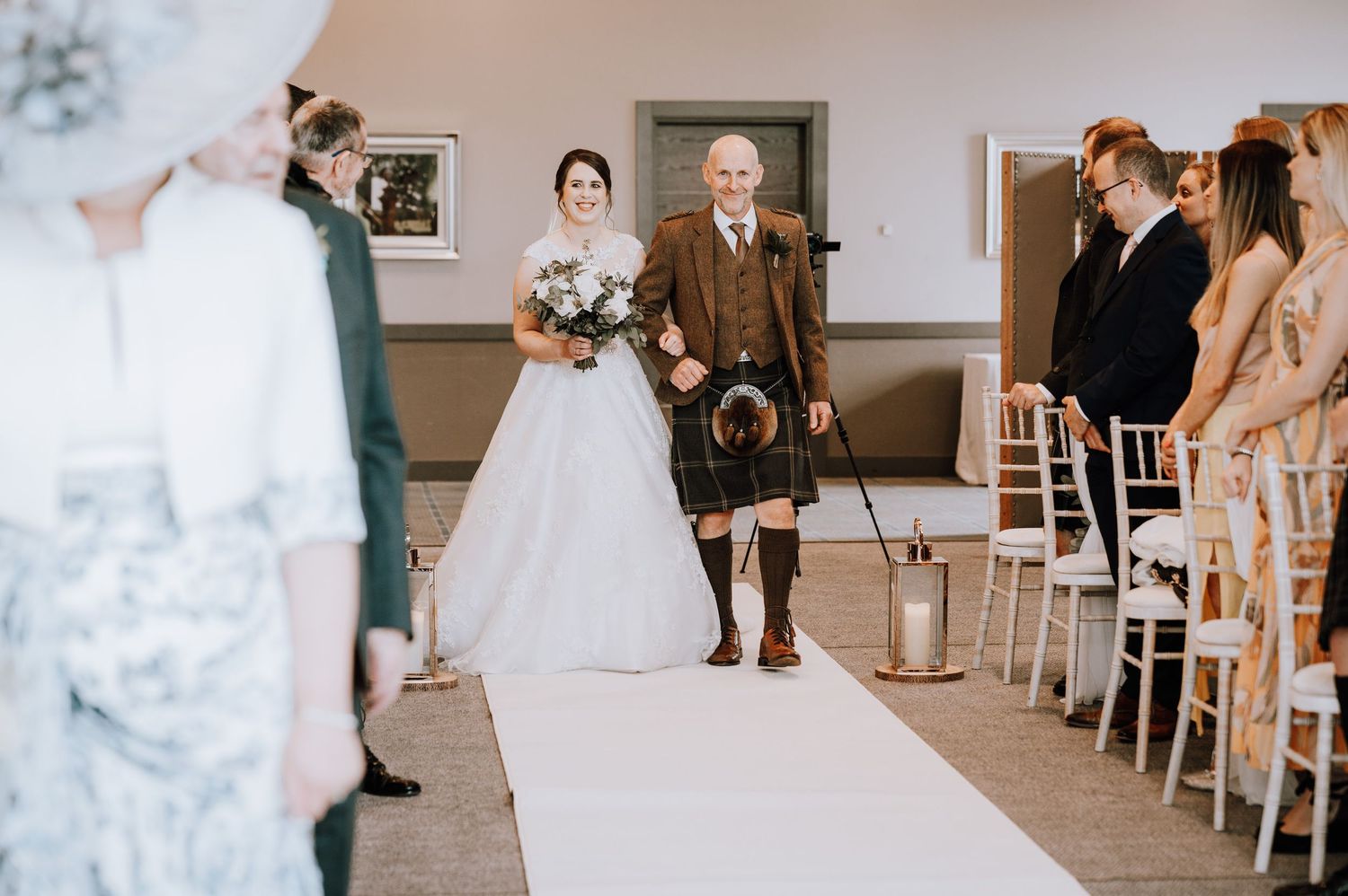 Intimate indoor wedding ceremony with white chairs and natural lighting. Meldrum House Wedding Photography.