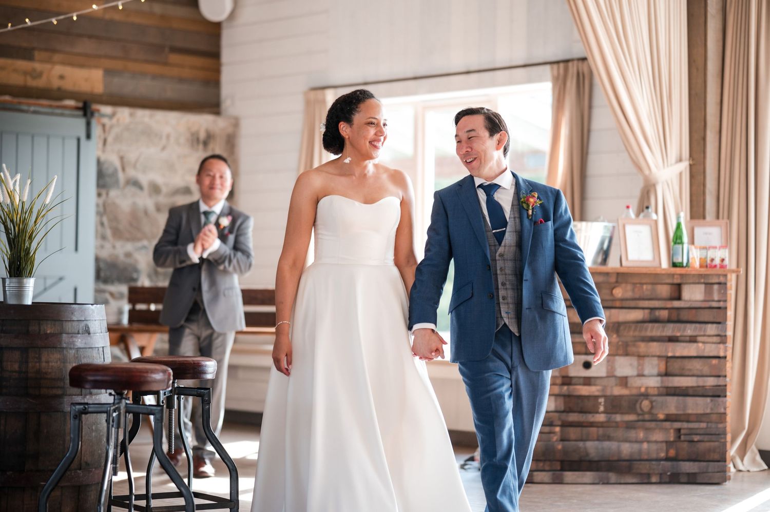 Wedding celebration in a rustic venue with string lights and white drapes.