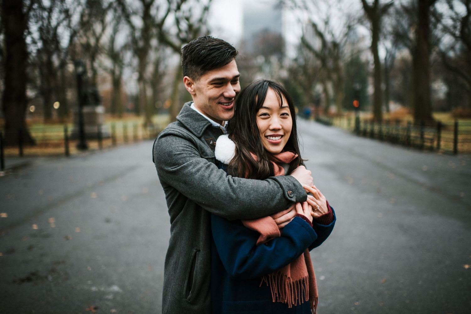 A joyful couple shares a laugh while embracing on a path in Central Park.