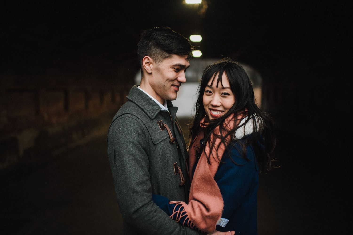 A couple shares a joyful moment together in a dimly lit indoor space.