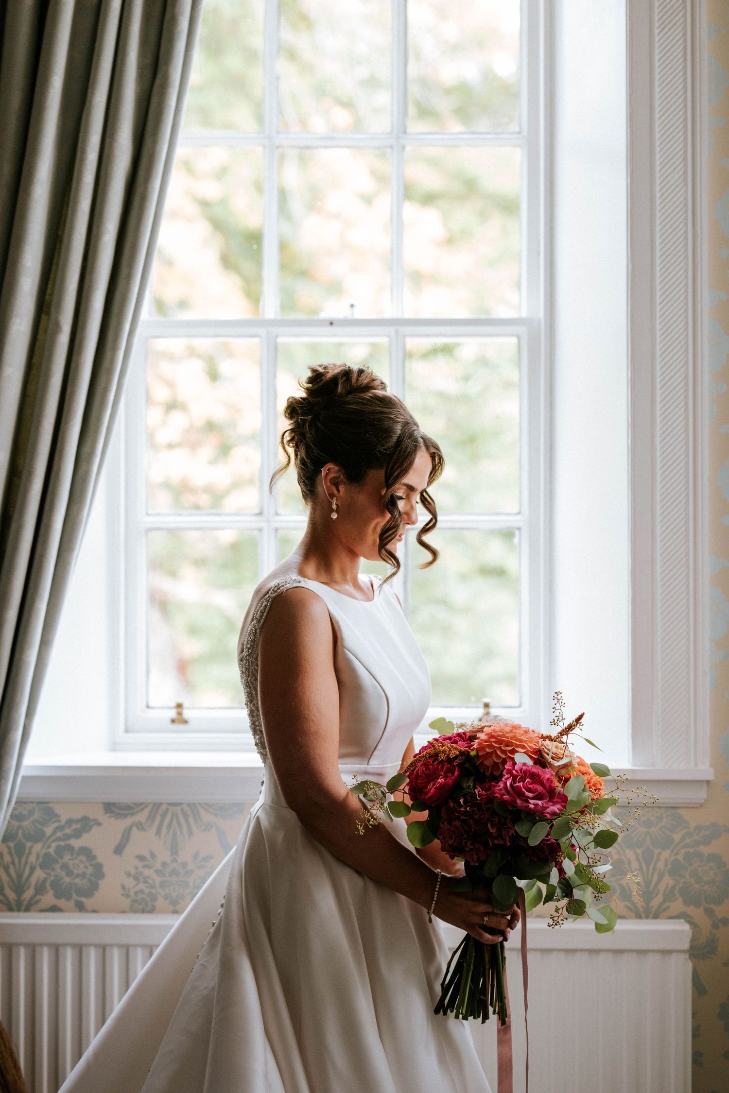 Elegant bridal portraits by a window with soft natural lighting and flowing curtains.