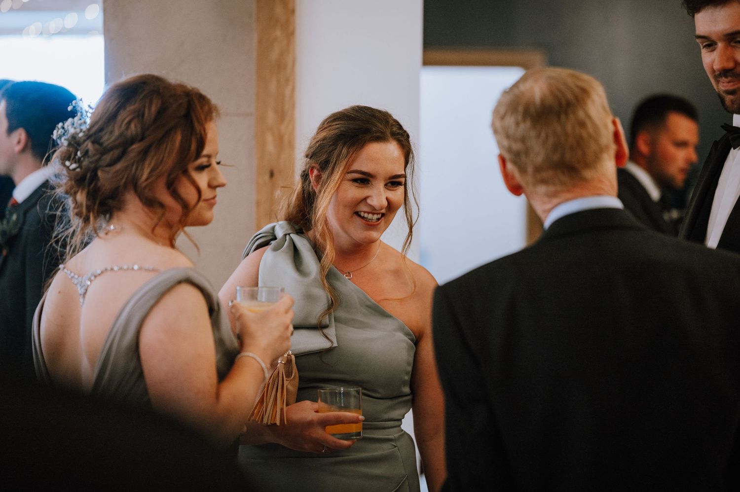 Wedding guests socializing with drinks at an indoor reception venue.