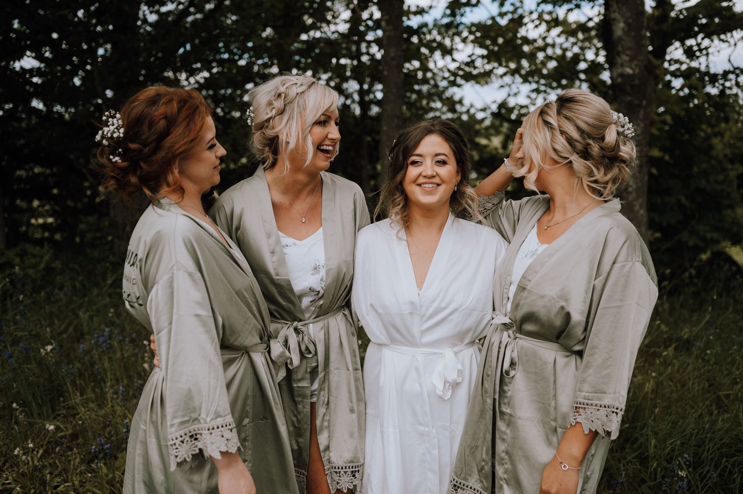 A group shares laughter while wearing coordinated grey and white robes in a outdoor setting.