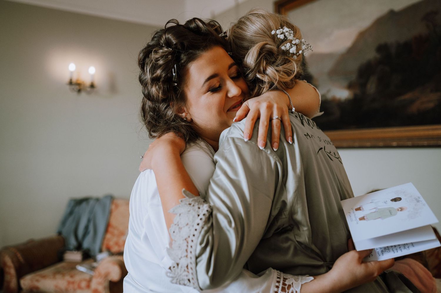 Two people share an emotional embrace while holding a white envelope.