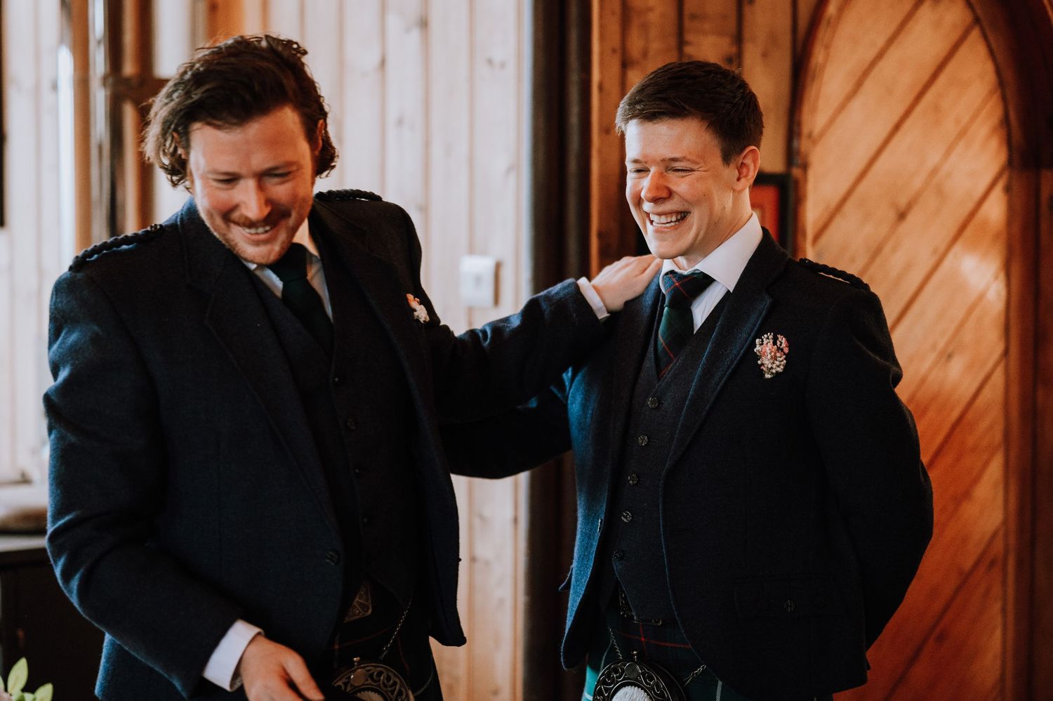 Two people in formal attire share a lighthearted moment at an indoor event.