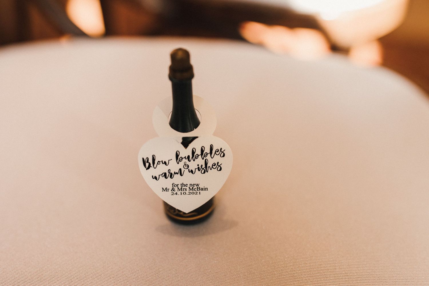 Small decorative black bottle with white handwritten text on a light surface.