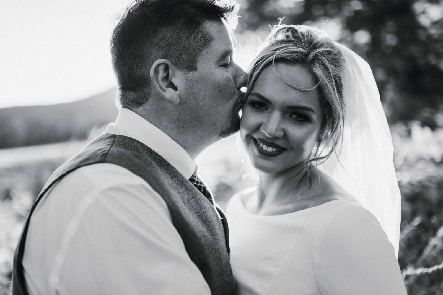 Close-up black and white wedding portrait capturing joyful moment between newlyweds.