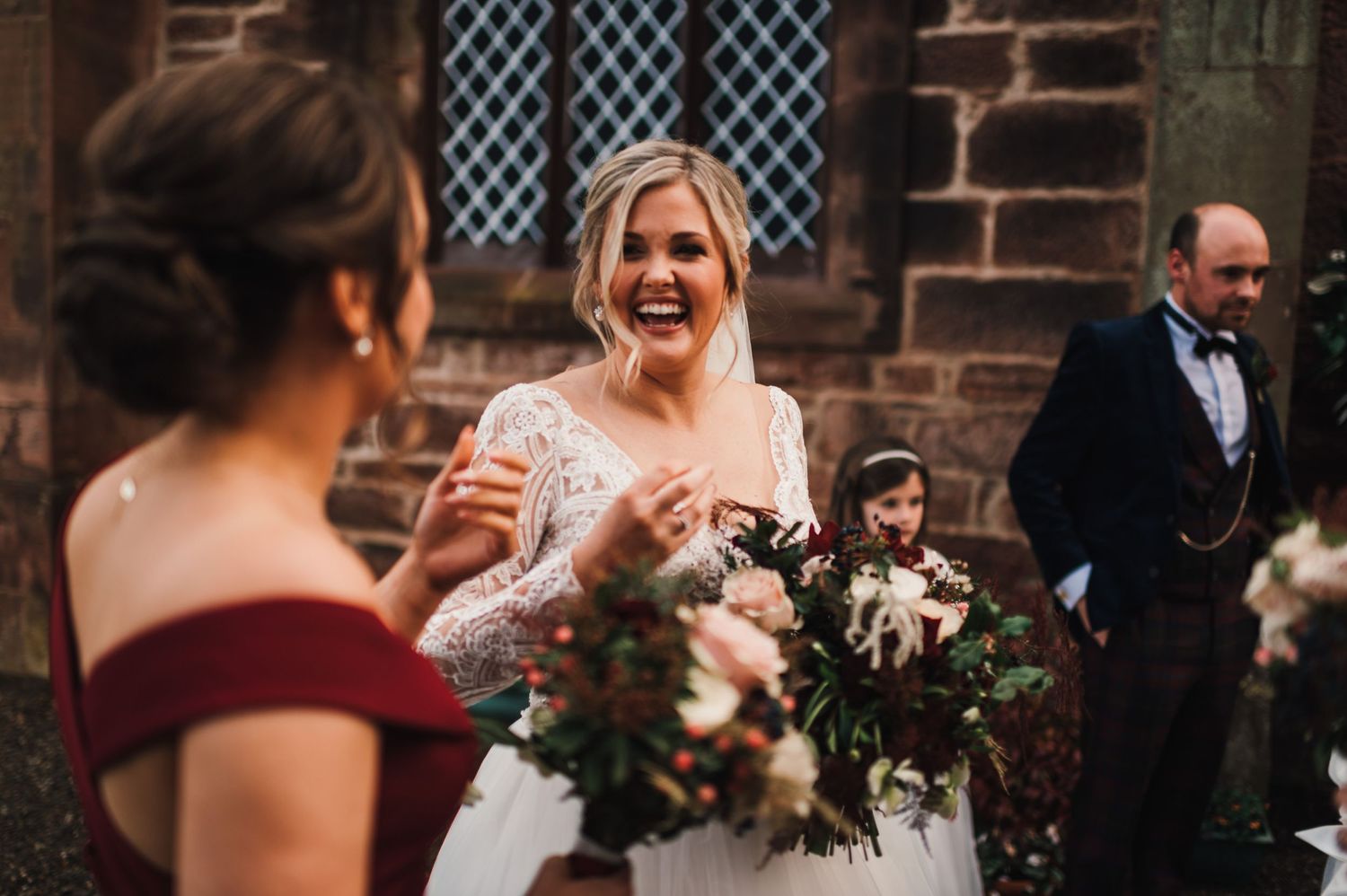 Candid celebration moment outside historic brick church during winter wedding.