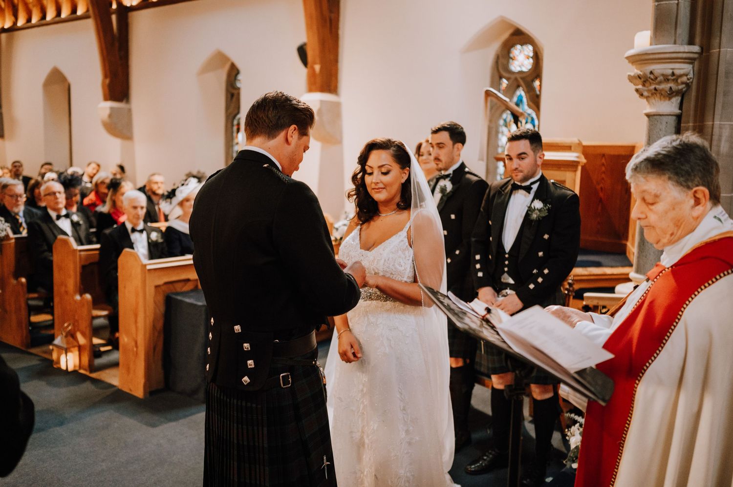 A Scottish wedding ceremony taking place in a historic church with traditional decorations.