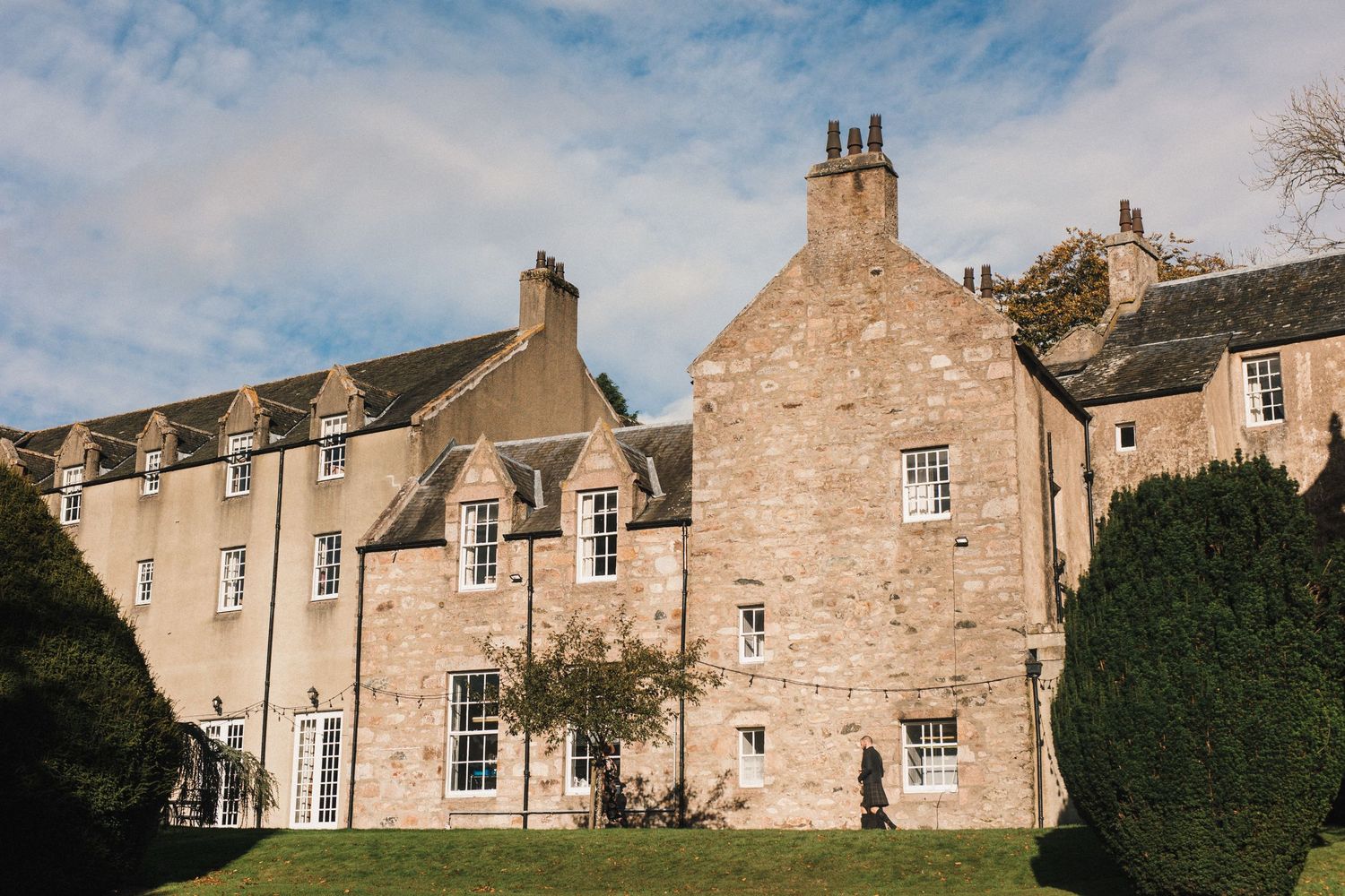 Historic Scottish stone mansion with traditional architecture and manicured hedges.