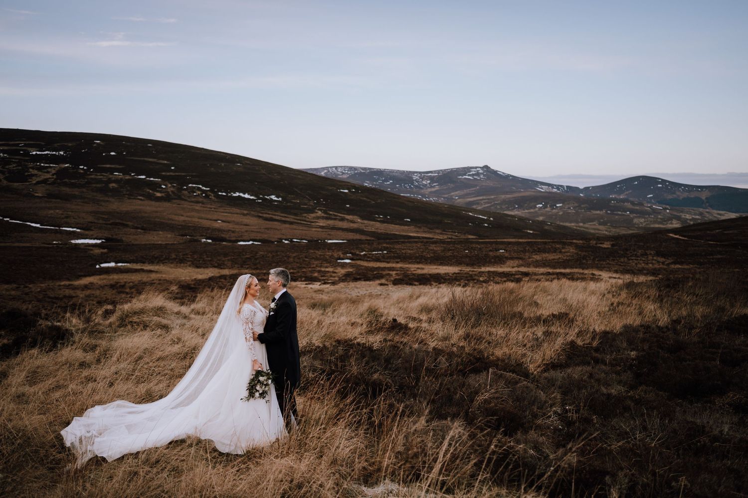 Romantic wedding photo overlooking vast highland wilderness landscape.