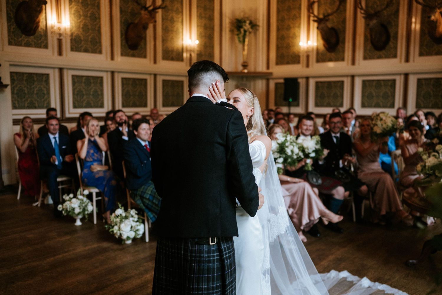 Wedding celebration in a luxurious ballroom with decorative wall panels and warm lighting.
