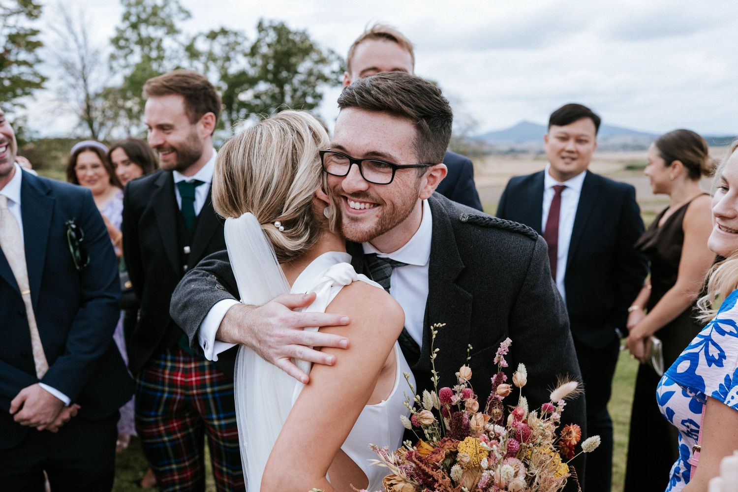 Wedding party and guests celebrating during an outdoor reception.