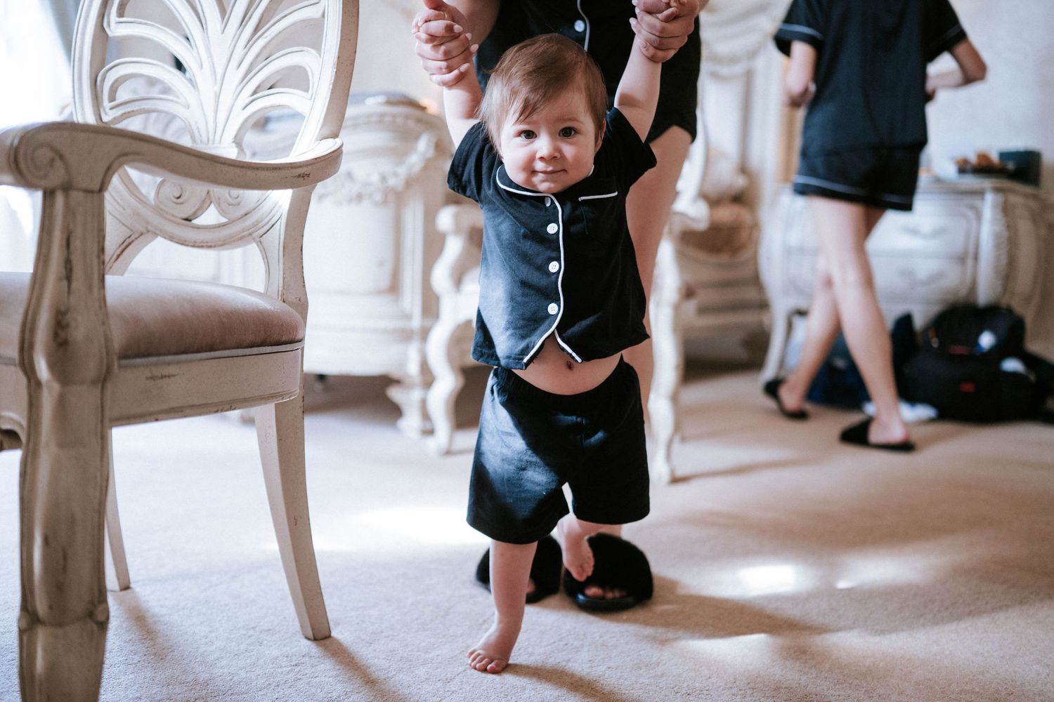 Wedding party poses playfully in an elegant indoor venue with ornate chairs and decor.