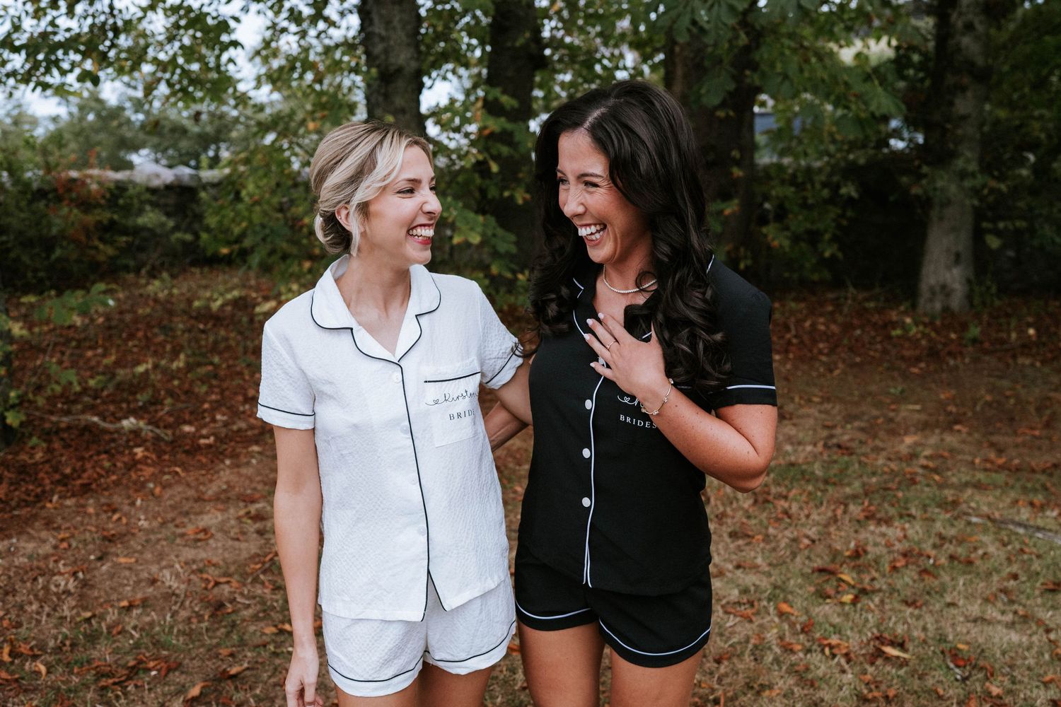 Two friends sharing a laugh while wearing matching pajama sets outdoors.