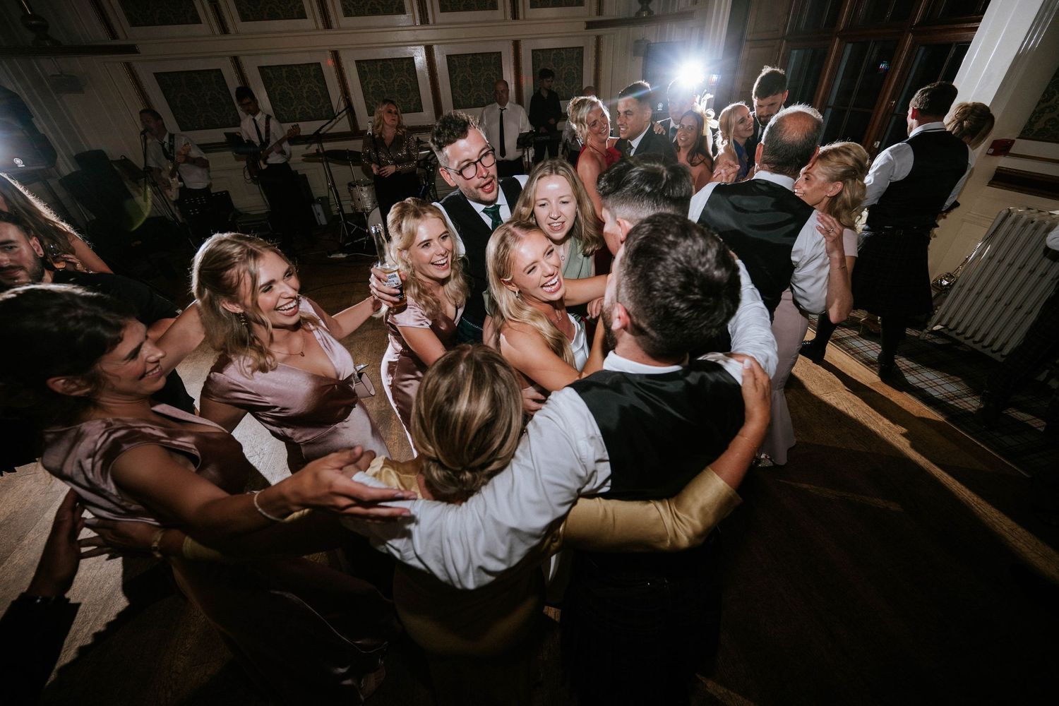 Wedding reception dance party with dramatic lighting and silhouetted guests on dance floor.