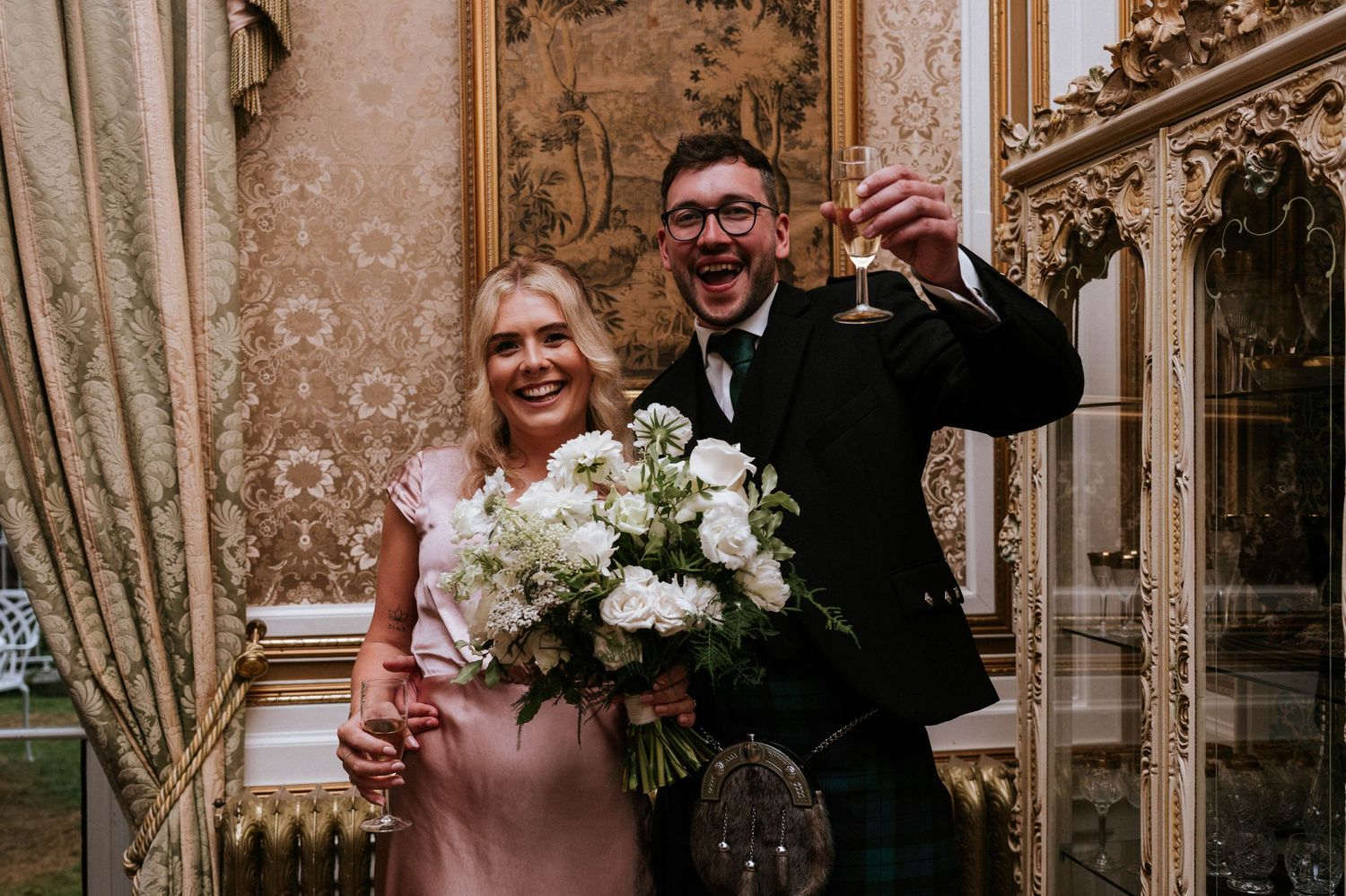 Wedding celebration in an ornate room with gold details and elegant curtains.