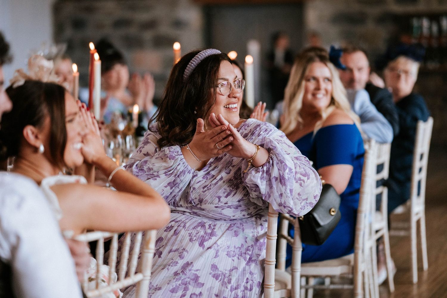 Wedding reception guests enjoying themselves at tables decorated with floral centerpieces.
