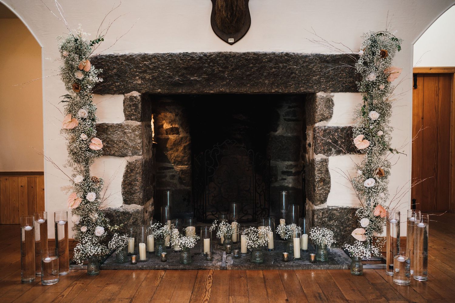 Stone fireplace decorated with floral garlands and candles for a wedding reception.